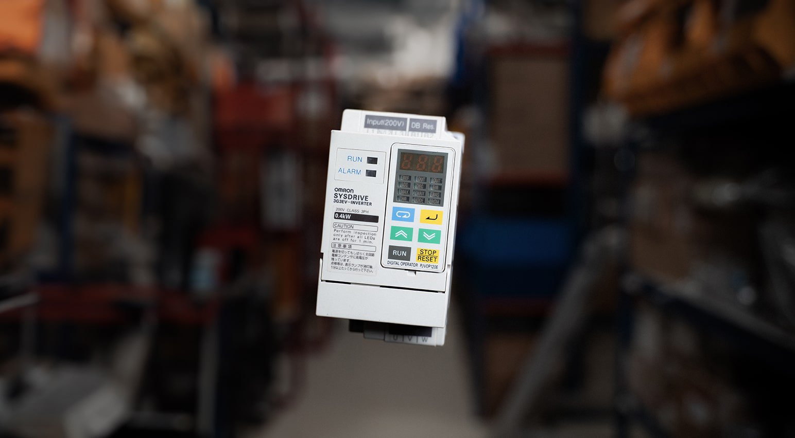 One automation part suspended in the air. The automation part is a white Sysdrive inverter, manufactured by Omron.